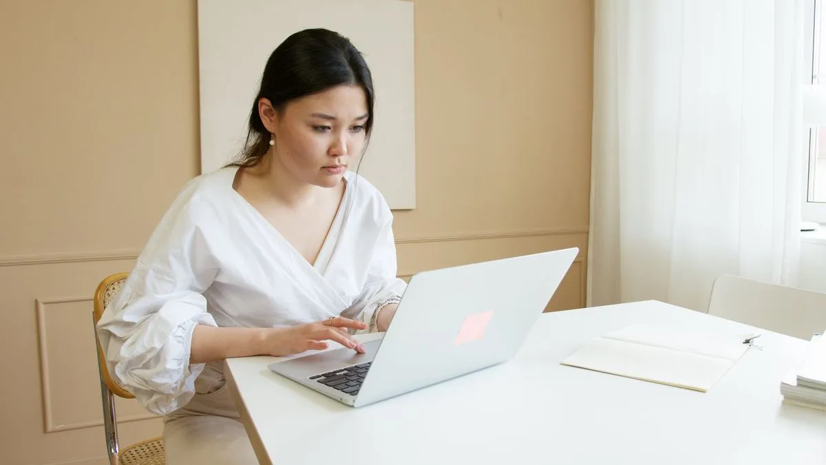 Woman in white top using macbook to cold outreach jobs